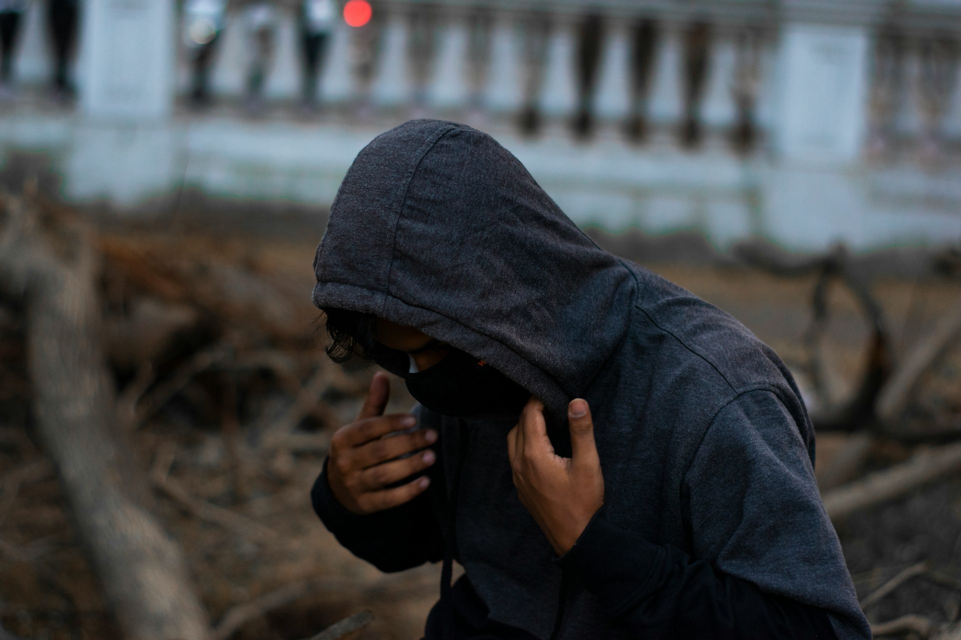 Person in dark gray hoodie, adjusting it outdoors.