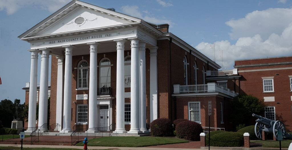 Brick courthouse with white columns, blue sky background.