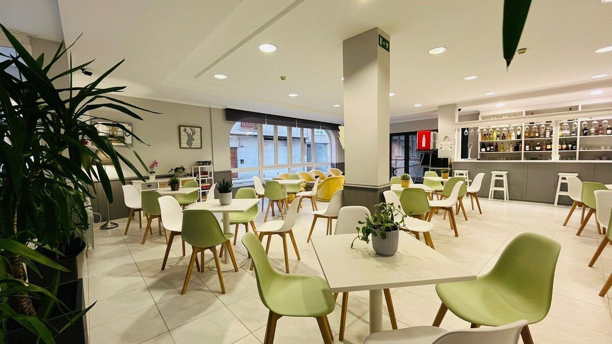 A bright dining area features light-colored square tables and lime green chairs, with a bar counter visible in the back.