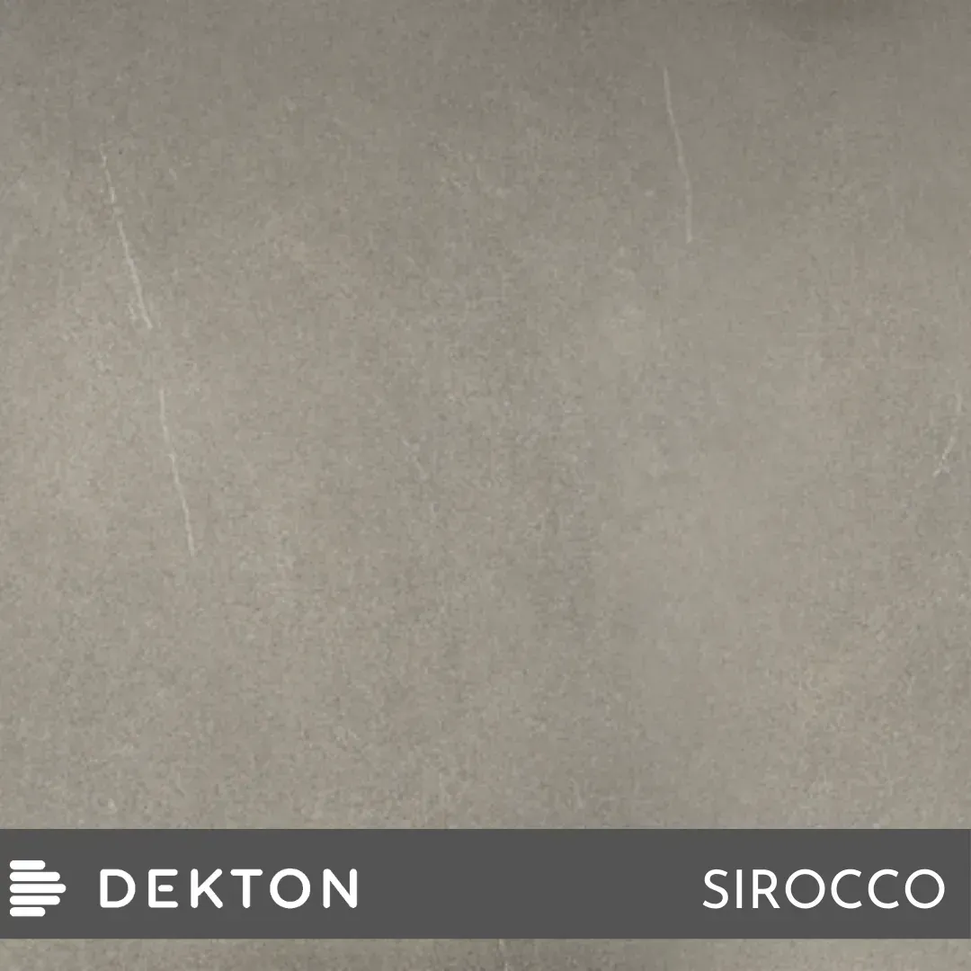 Superficie gris con aspecto de hormigón y una franja inferior oscura con las etiquetas “DEKTON” y “SIROCCO”.