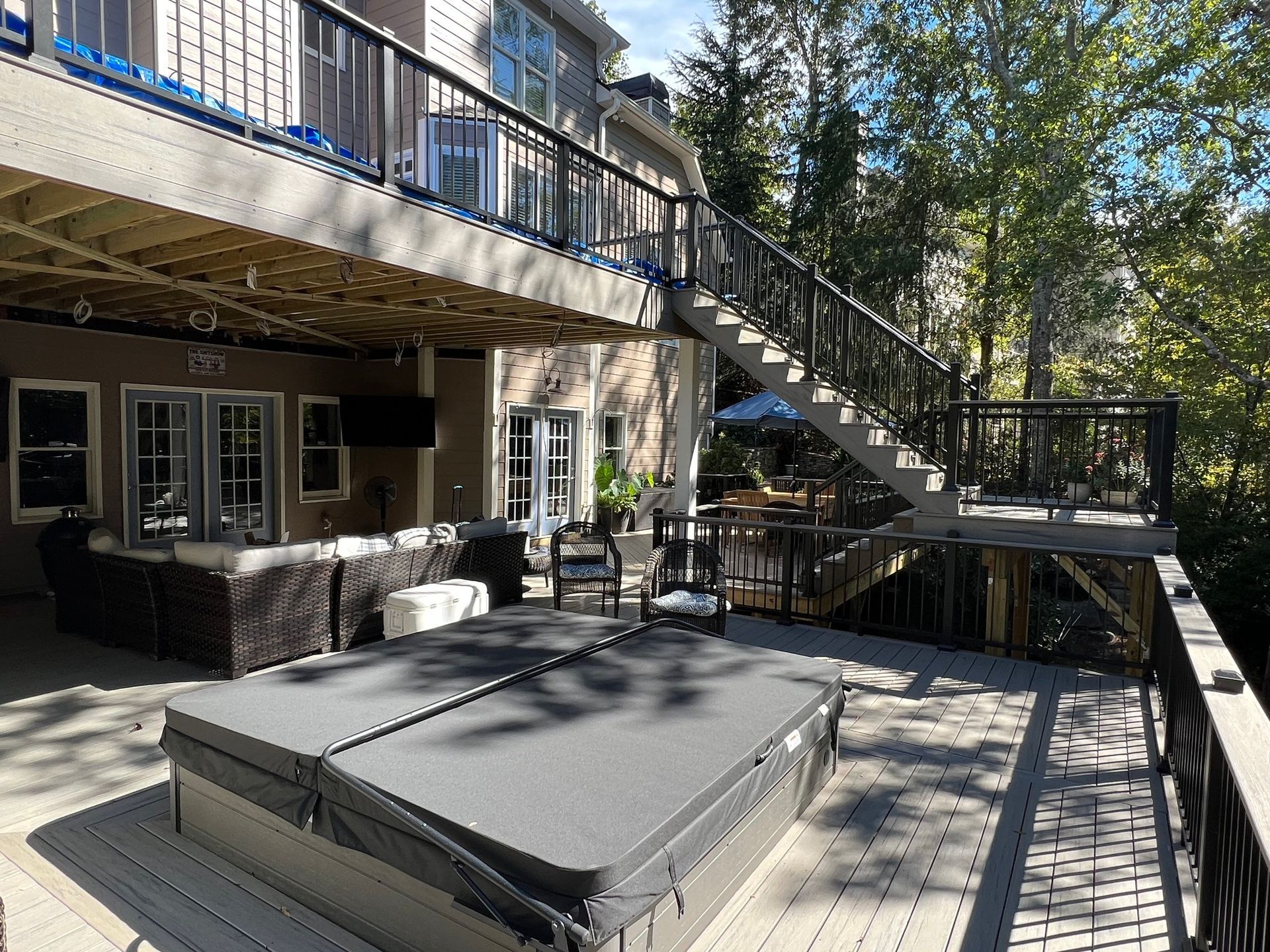 Multi-level deck with a hot tub, stairs, and a house in the background.