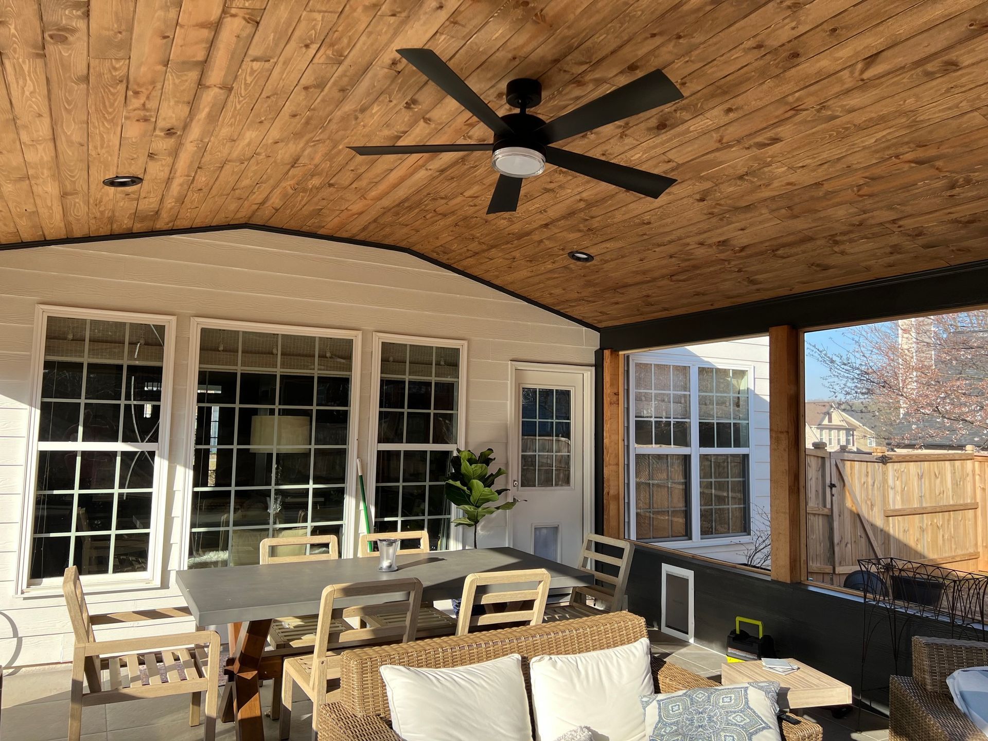 Covered patio with wood ceiling, fan, windows, and outdoor furniture.