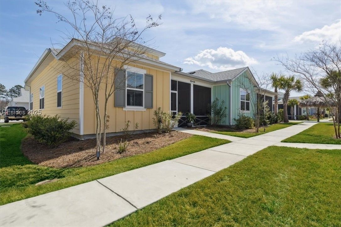 Row of colorful houses with walkways and green lawns under a blue sky.
