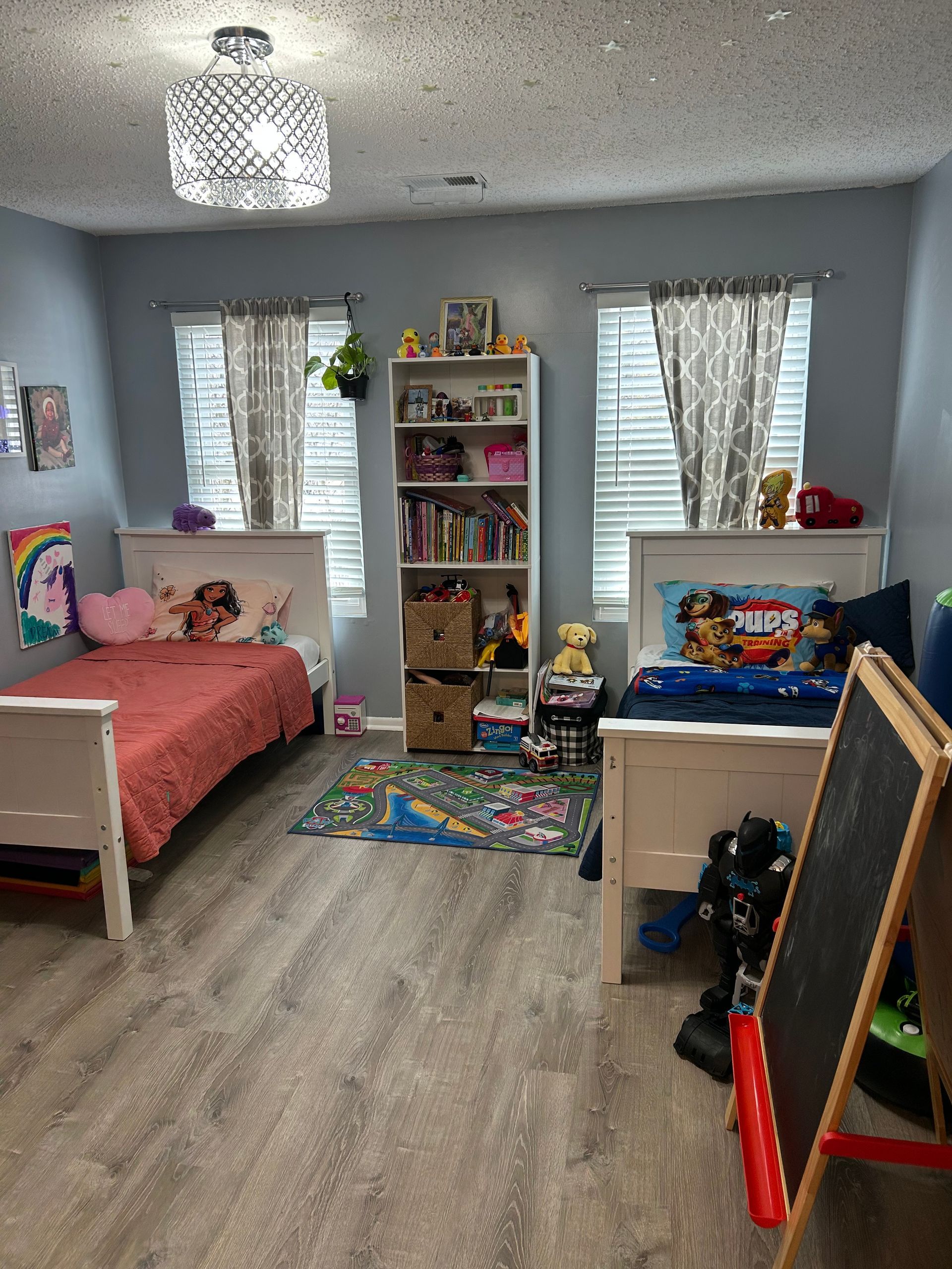 Bedroom with two twin beds, bookcase, and gray and white decor.