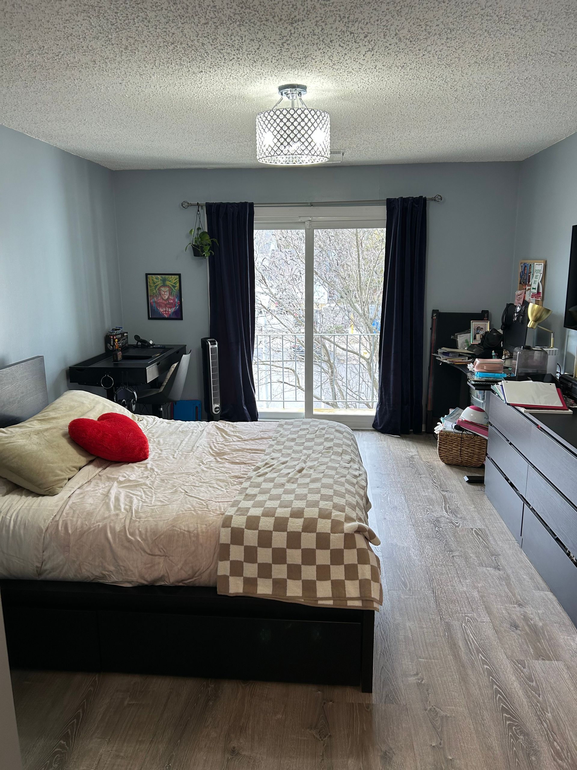 Bedroom with bed, blue walls, sliding glass door with navy curtains, and a chandelier.