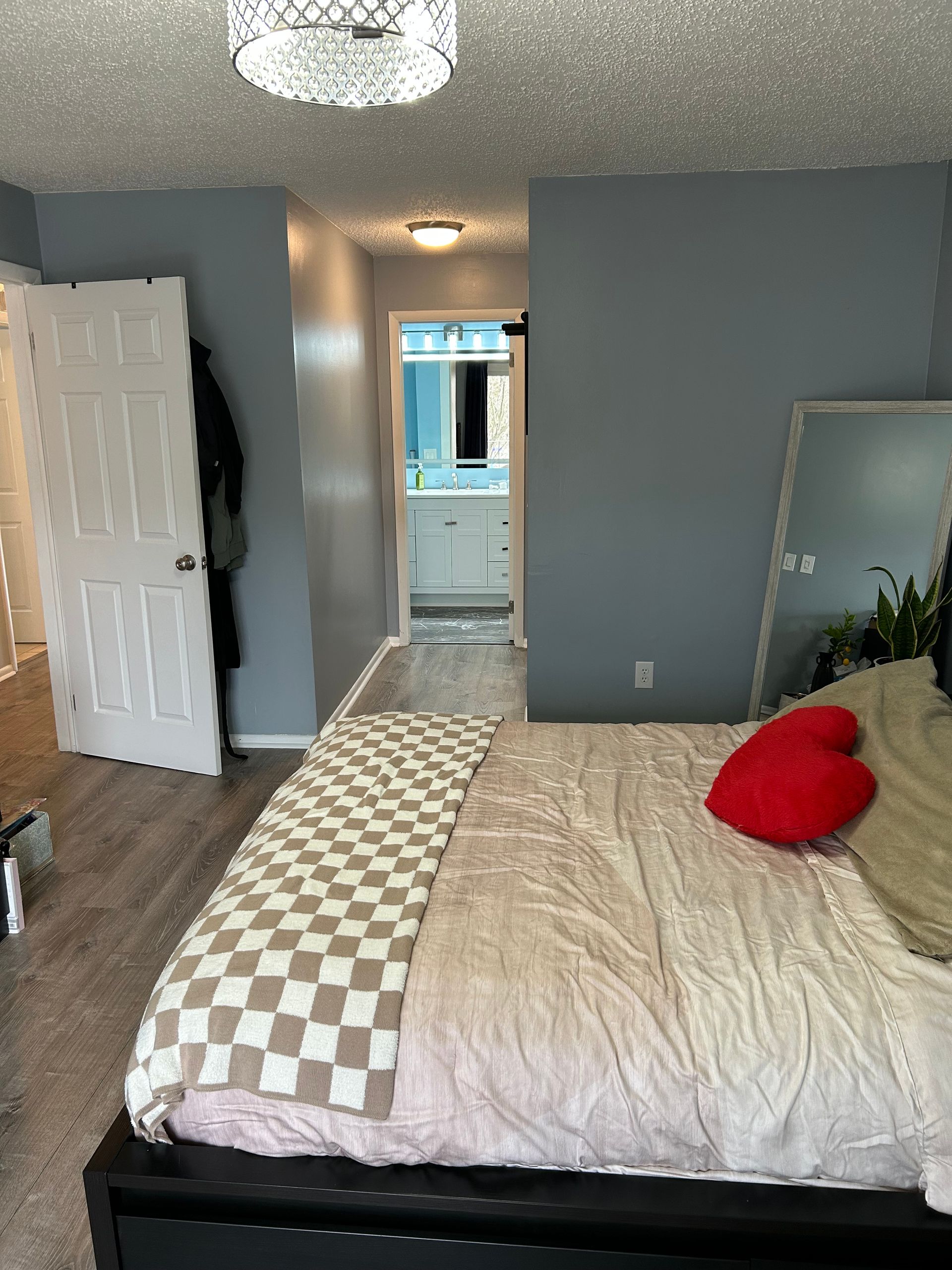 Bedroom with bed, blue walls, a door, and a hallway to a bathroom.