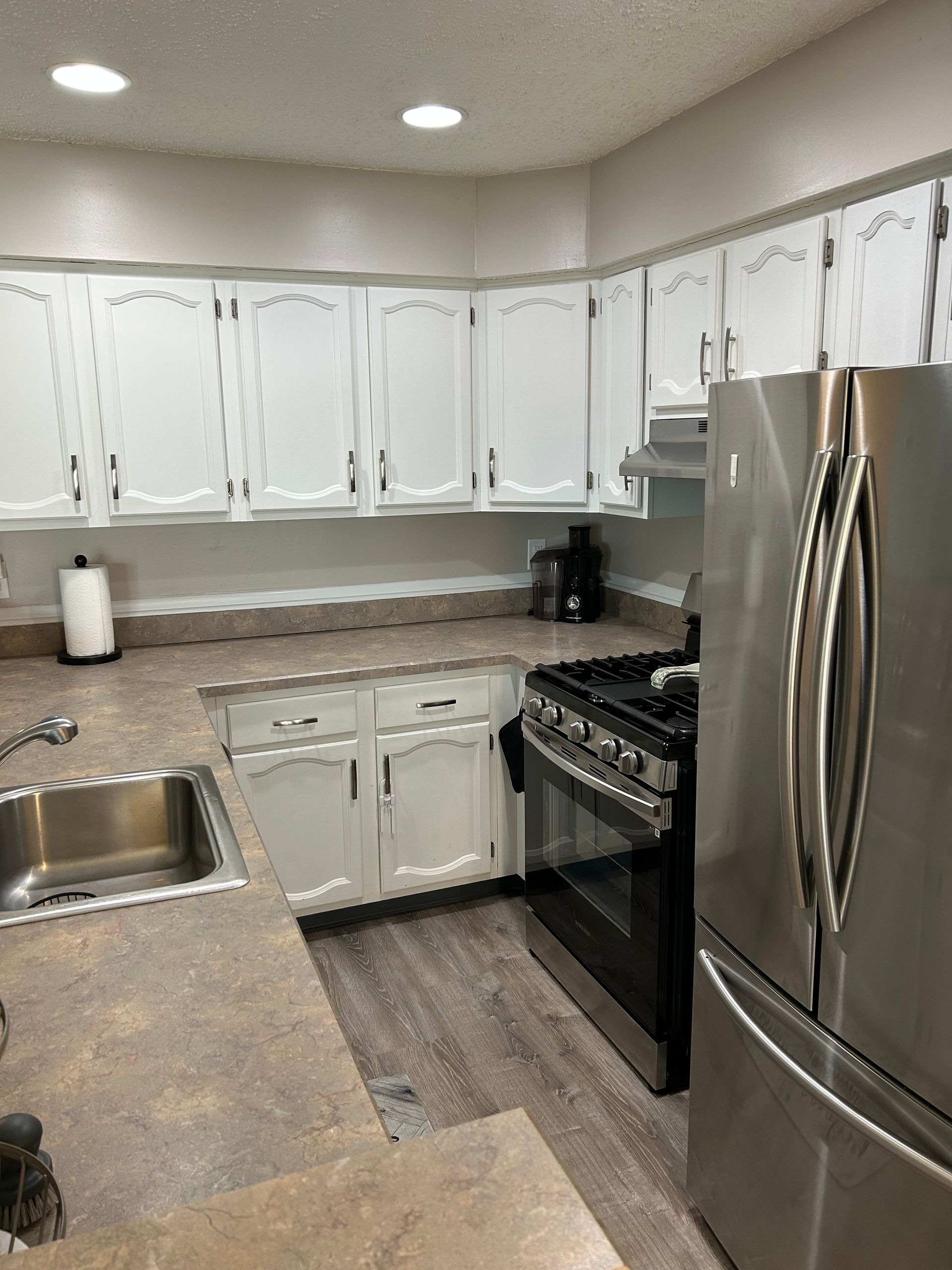 Kitchen with white cabinets, stainless steel appliances, and brown countertops.