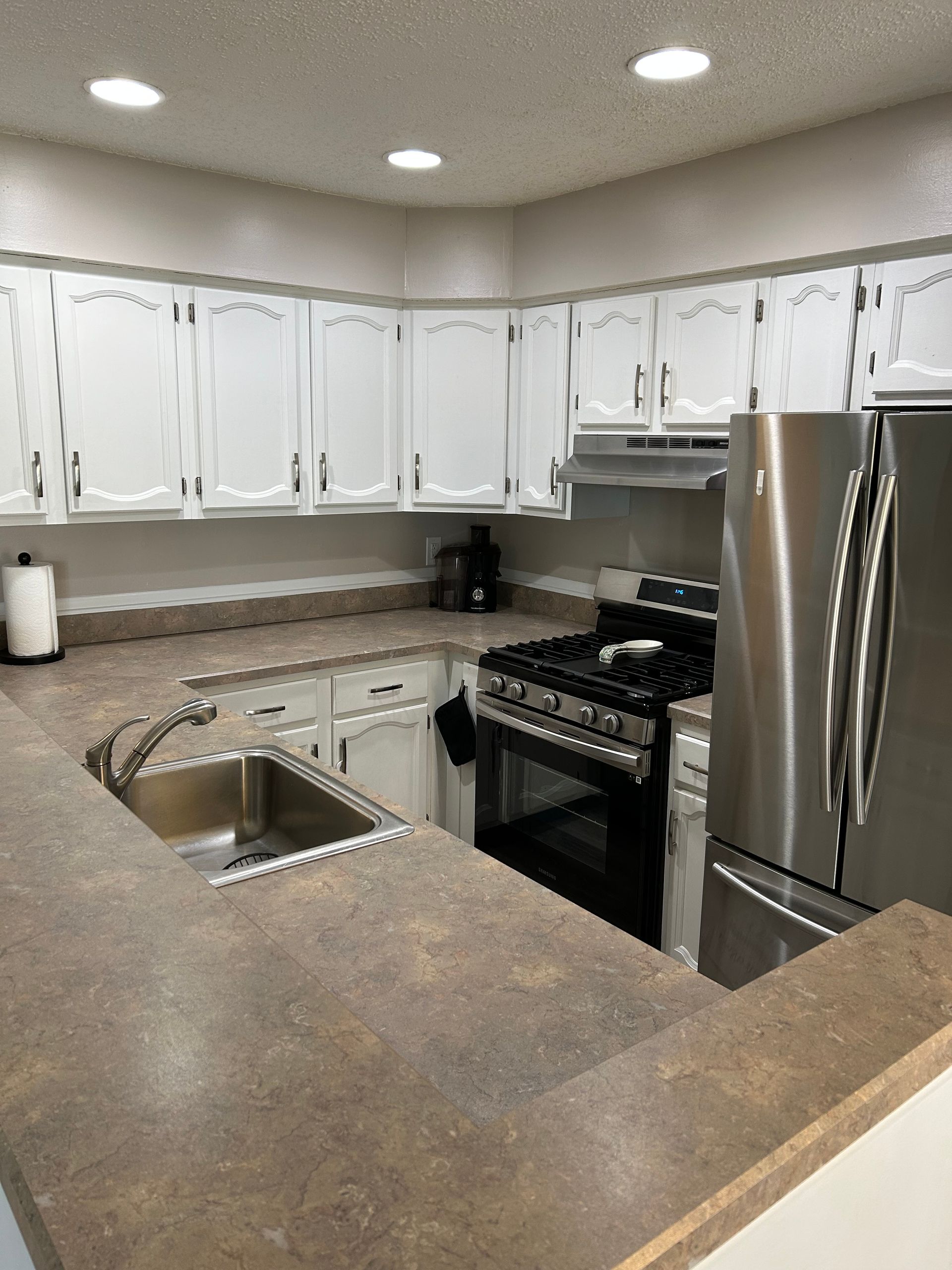 White kitchen cabinets and countertops with stainless steel appliances.