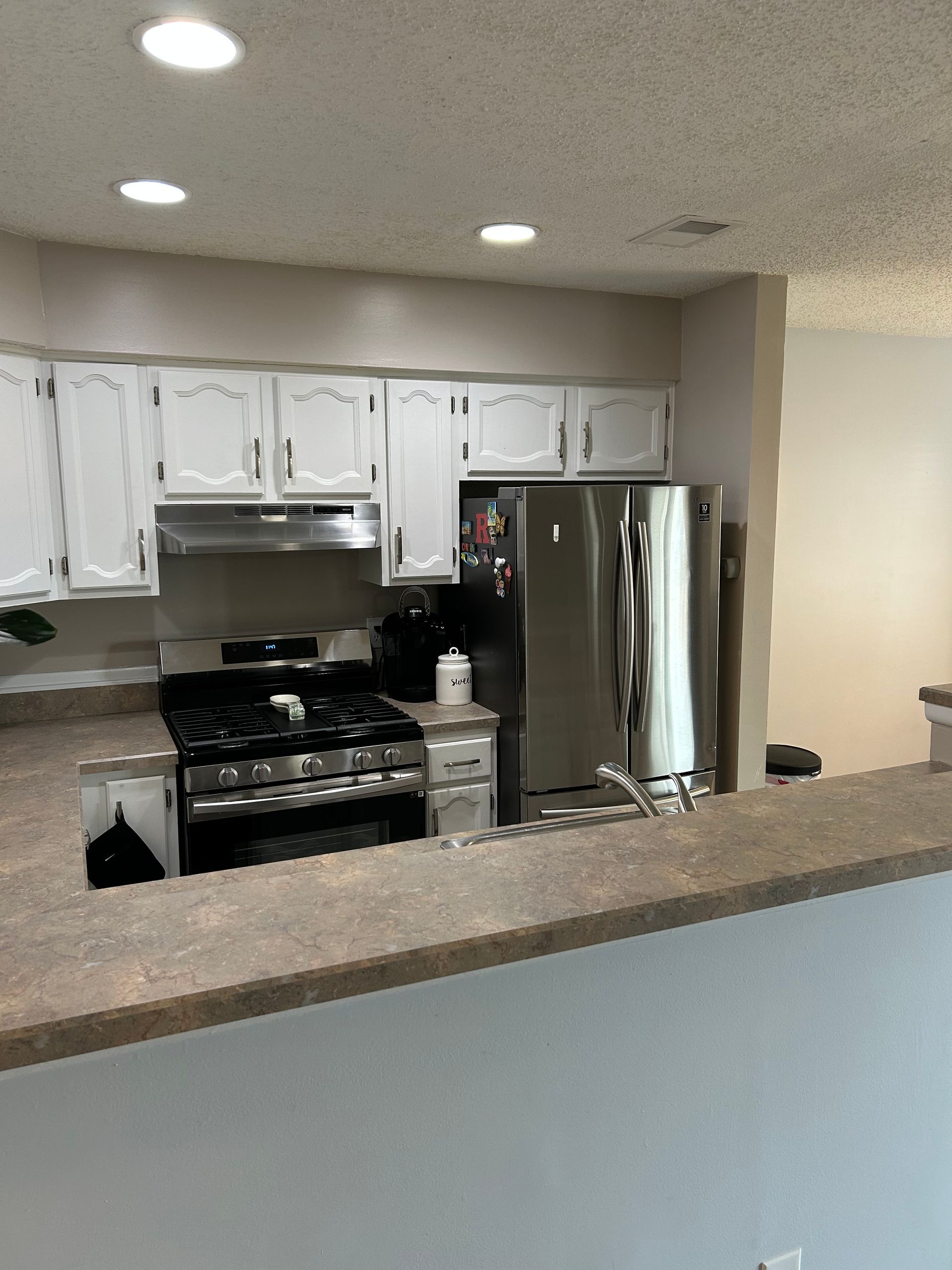 Kitchen with white cabinets, stainless steel appliances, and a gray countertop.