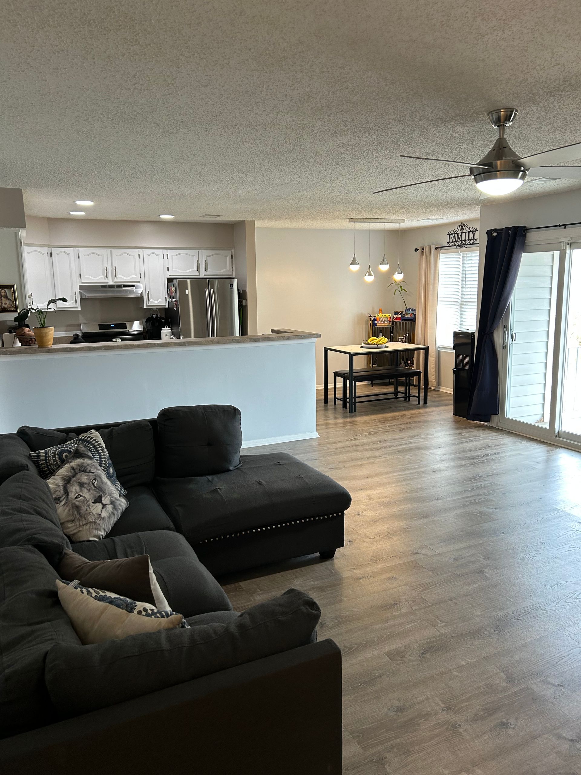 Living room with dark gray sectional sofa, open to a kitchen and dining area.