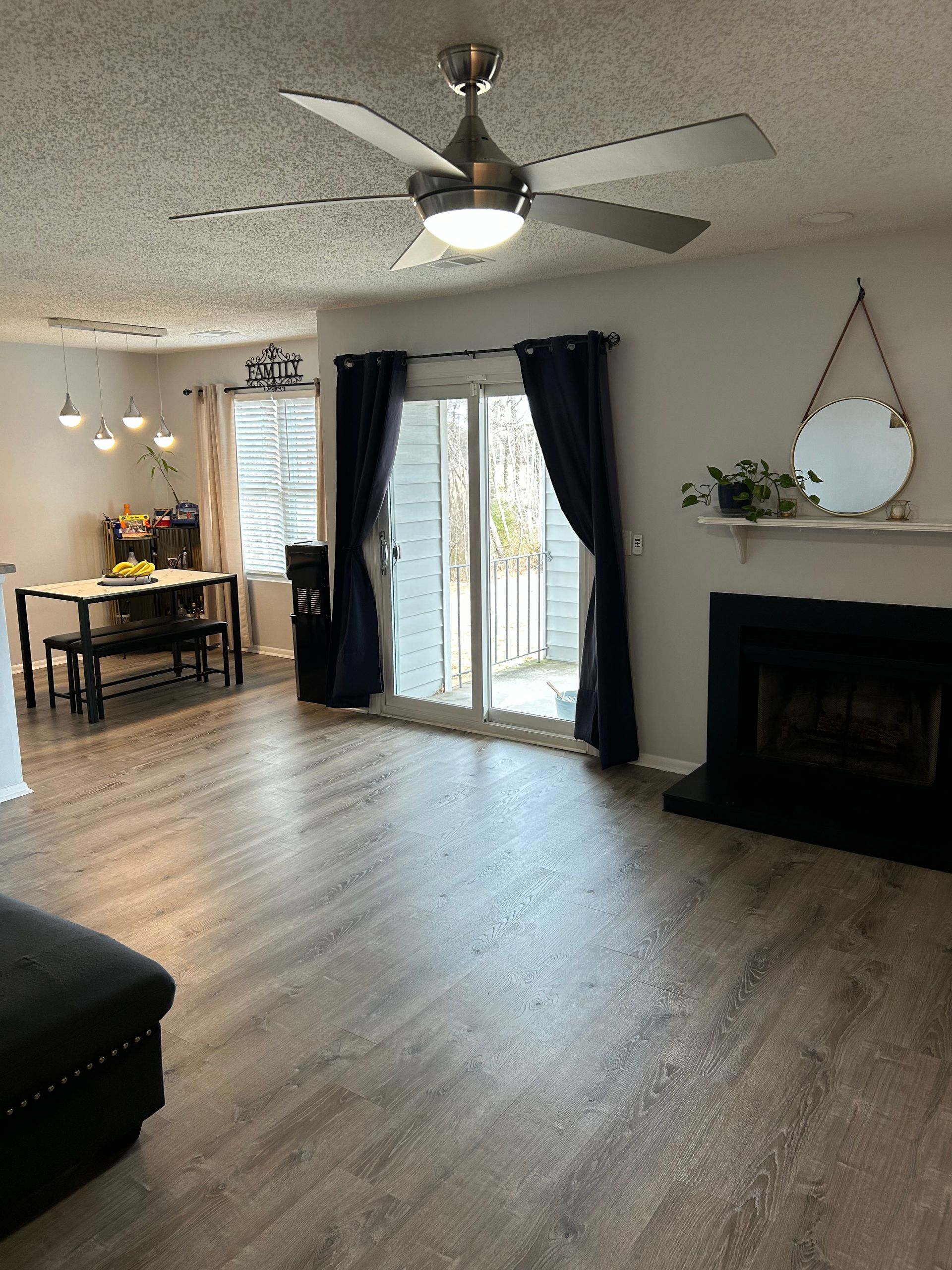 Living room with wood-look floor, sliding door to patio, fireplace, and dining area with a table.