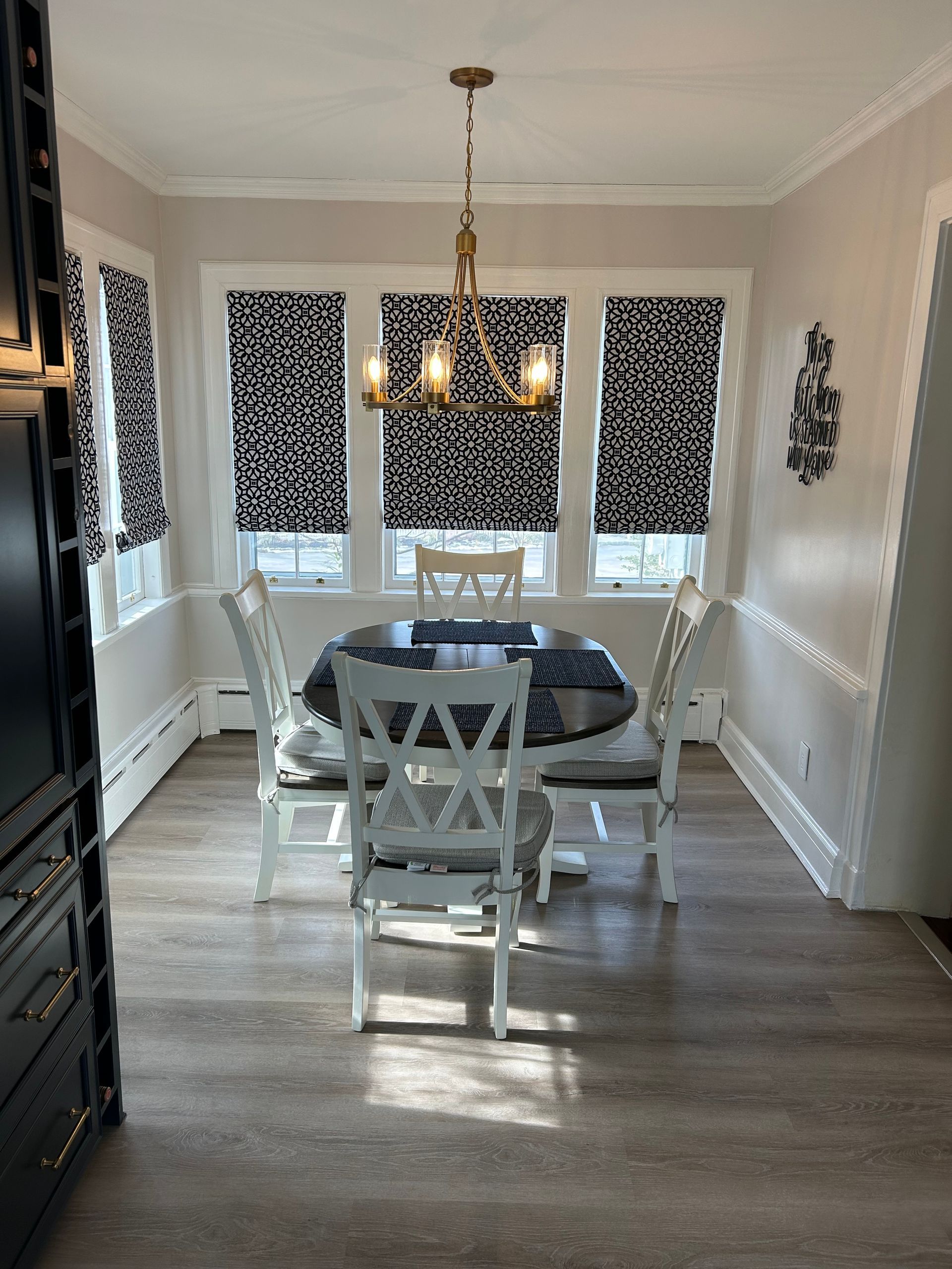 Dining room with table, chairs, patterned shades, and chandelier.