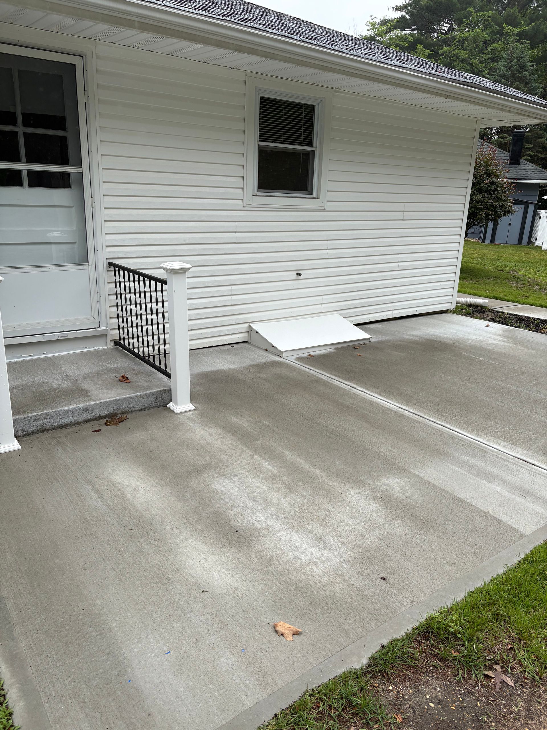 White house exterior with concrete patio and accessible ramp.