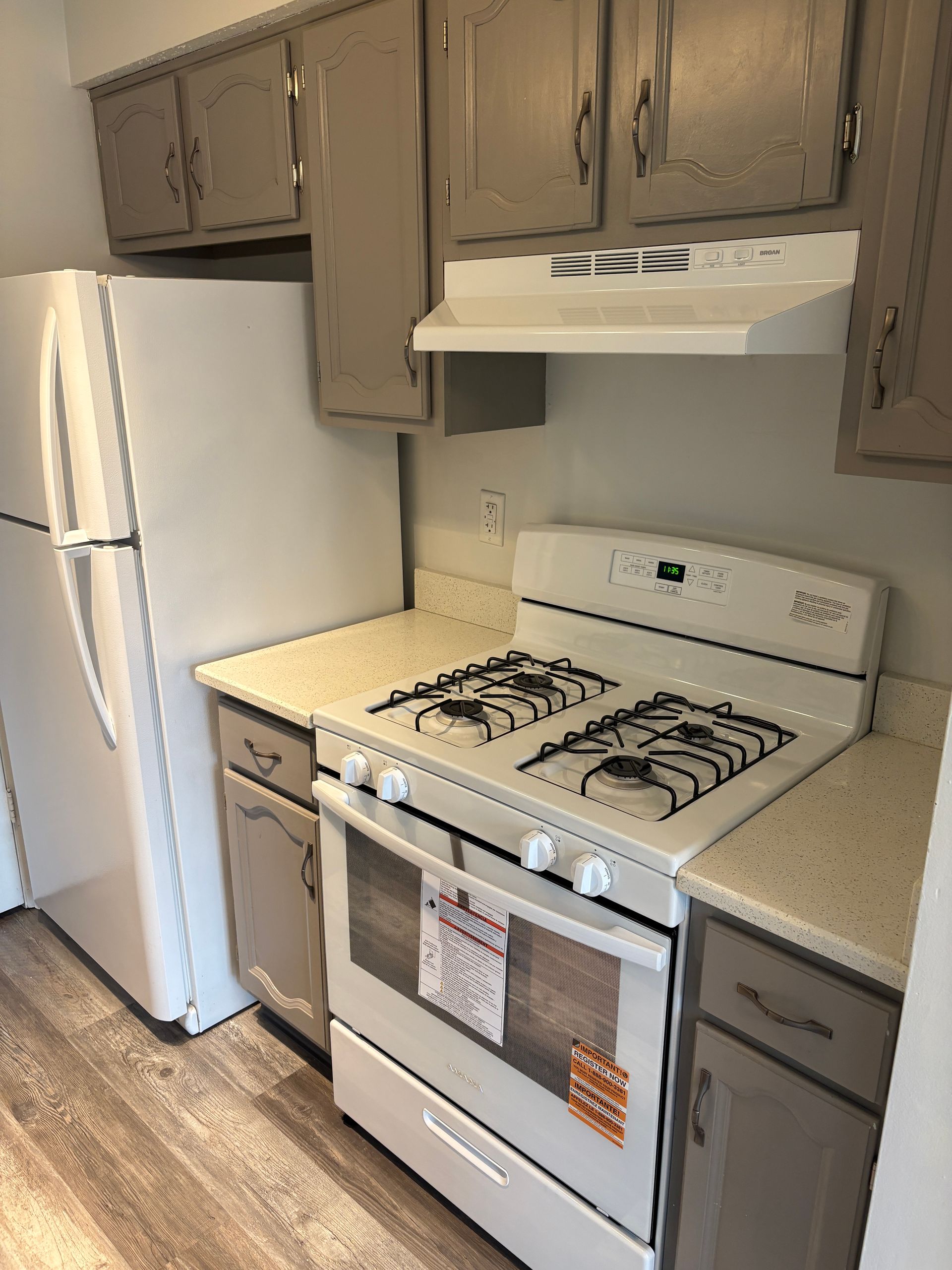 Kitchen with white appliances, gray cabinets, and light countertops.
