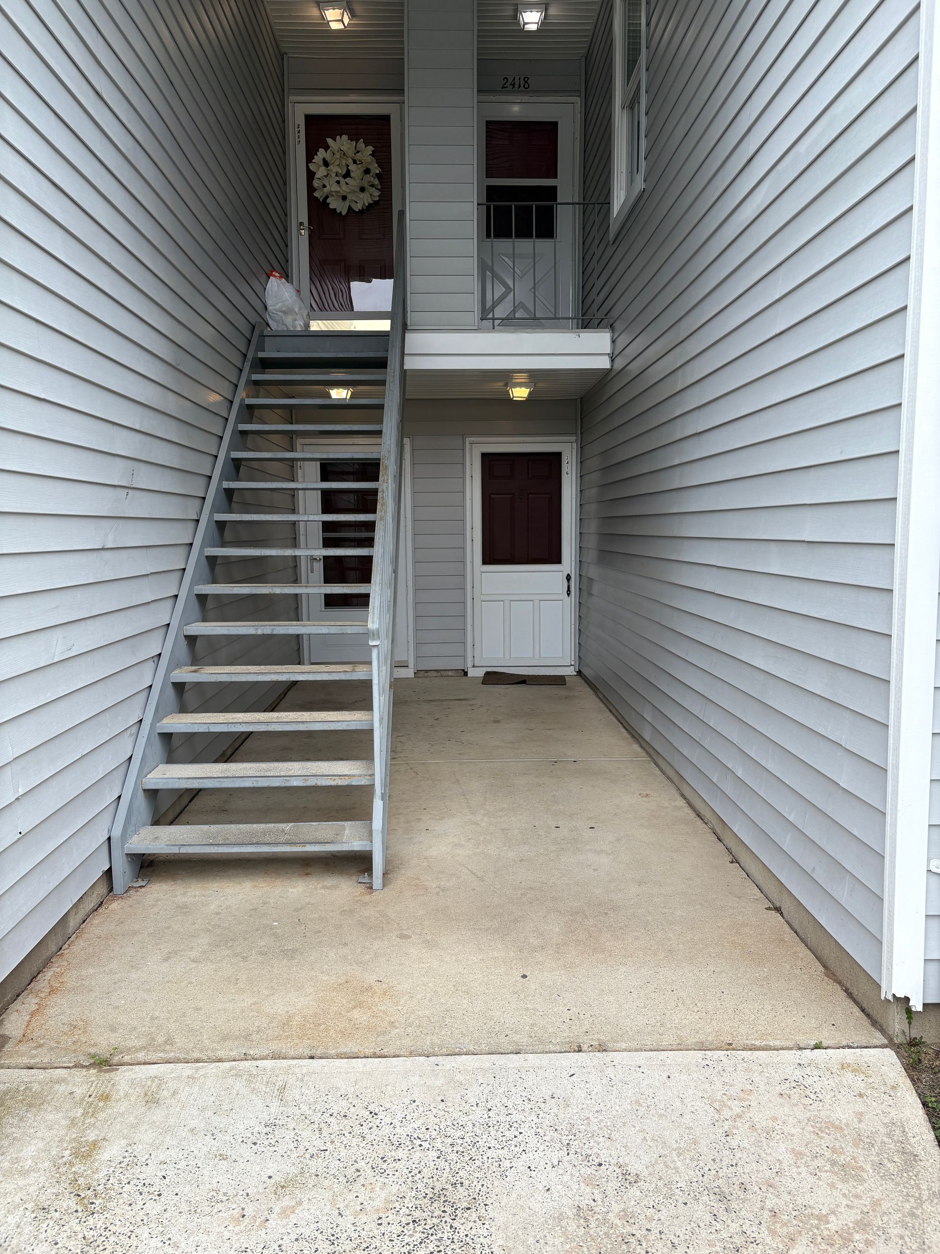 Exterior of a building with multiple doors and an external metal staircase leading to the upper level.