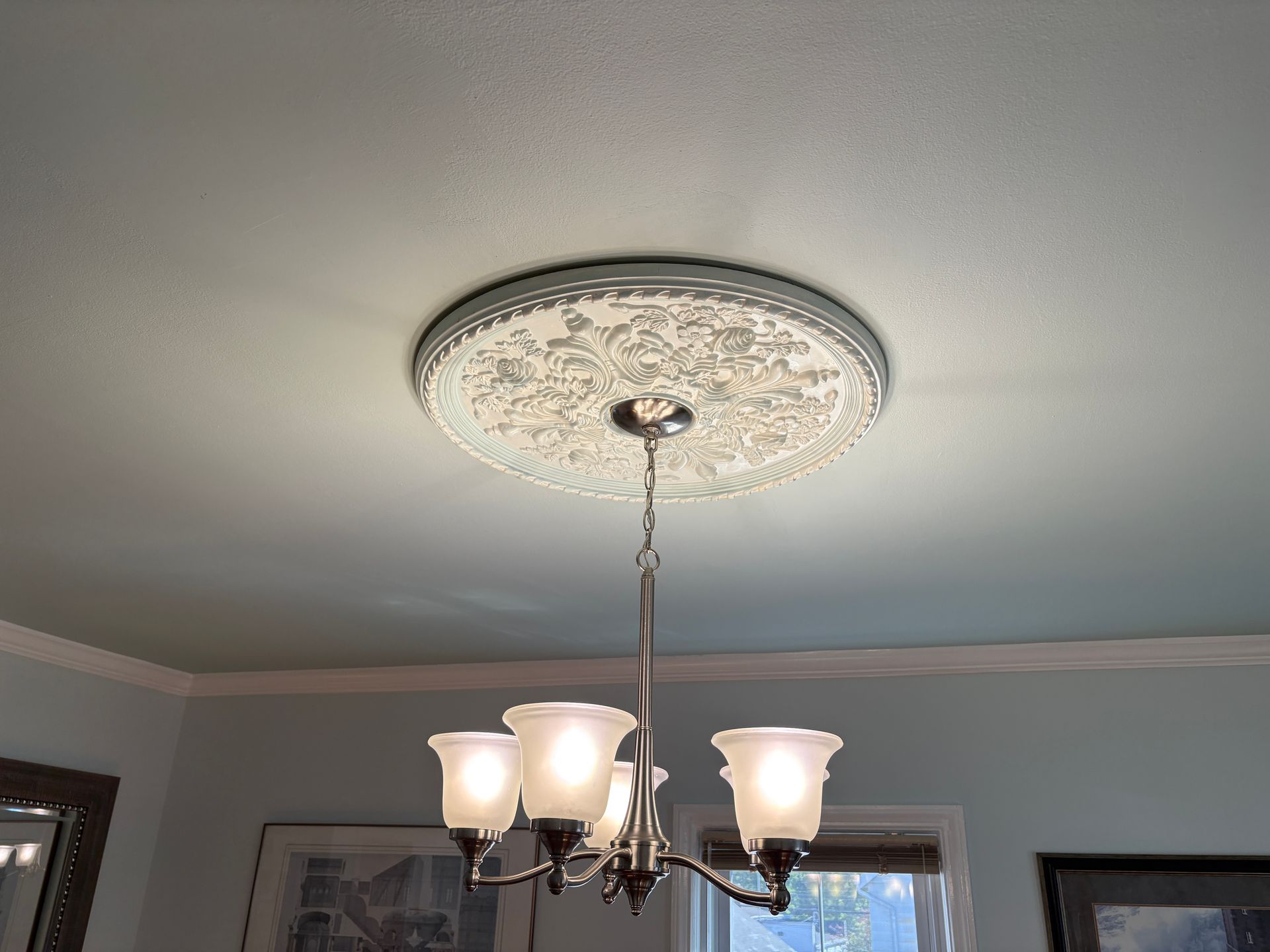 Chandelier hanging from a decorative ceiling medallion. The ceiling is pale blue and the walls are light blue.
