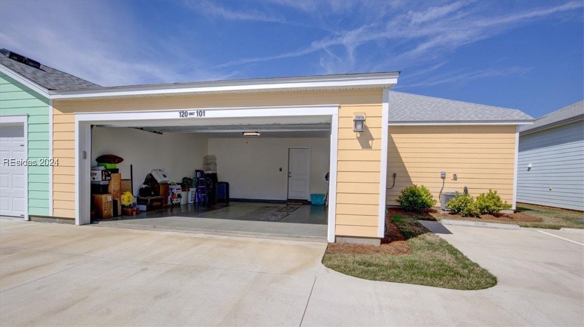 Open garage of a light yellow building. Contents inside include boxes, and storage. Blue sky overhead.