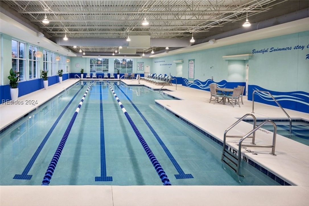 Indoor swimming pool with blue lane markers, a white deck, and light blue walls.