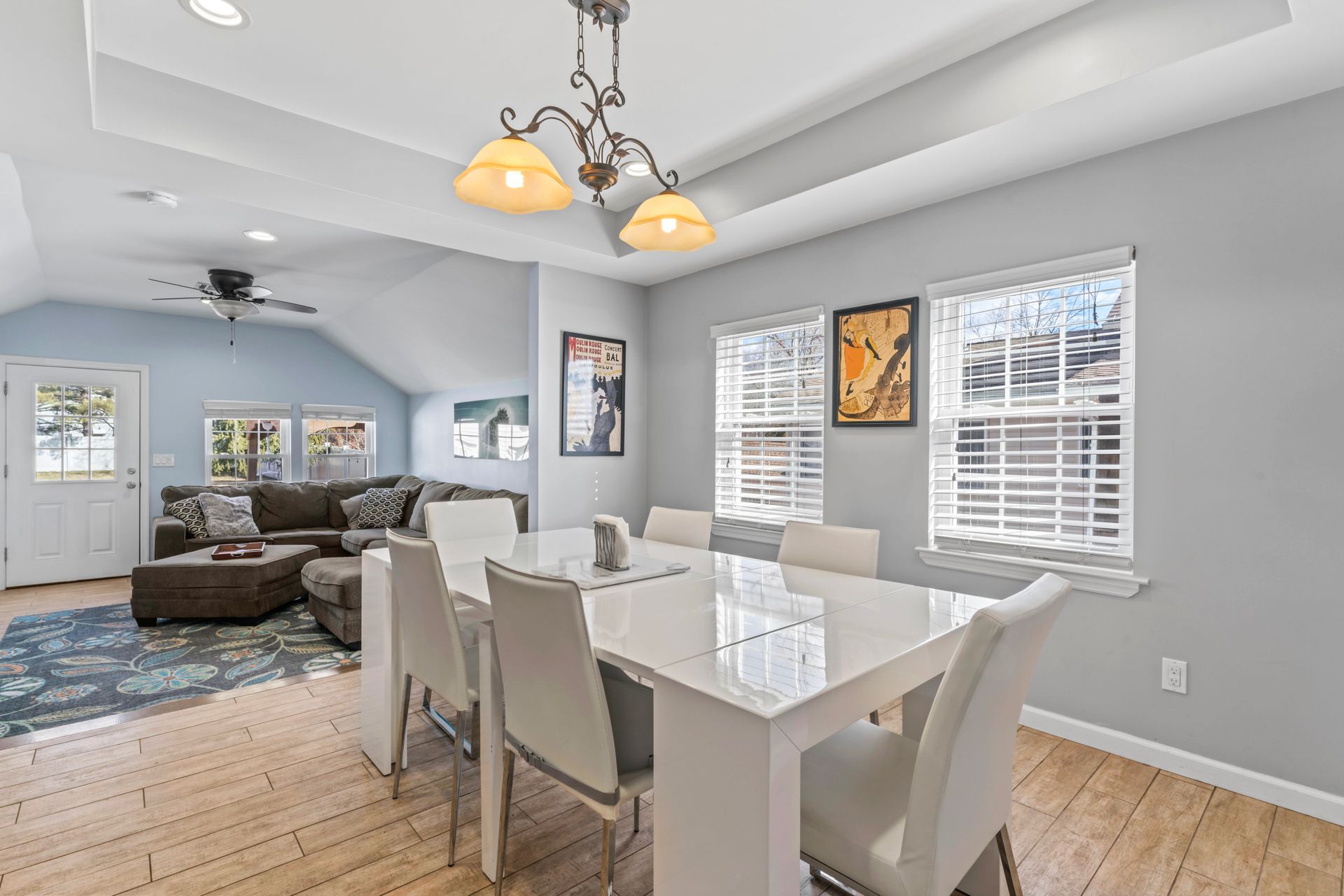 Dining room with white table and chairs, hardwood floors, and light blue walls.