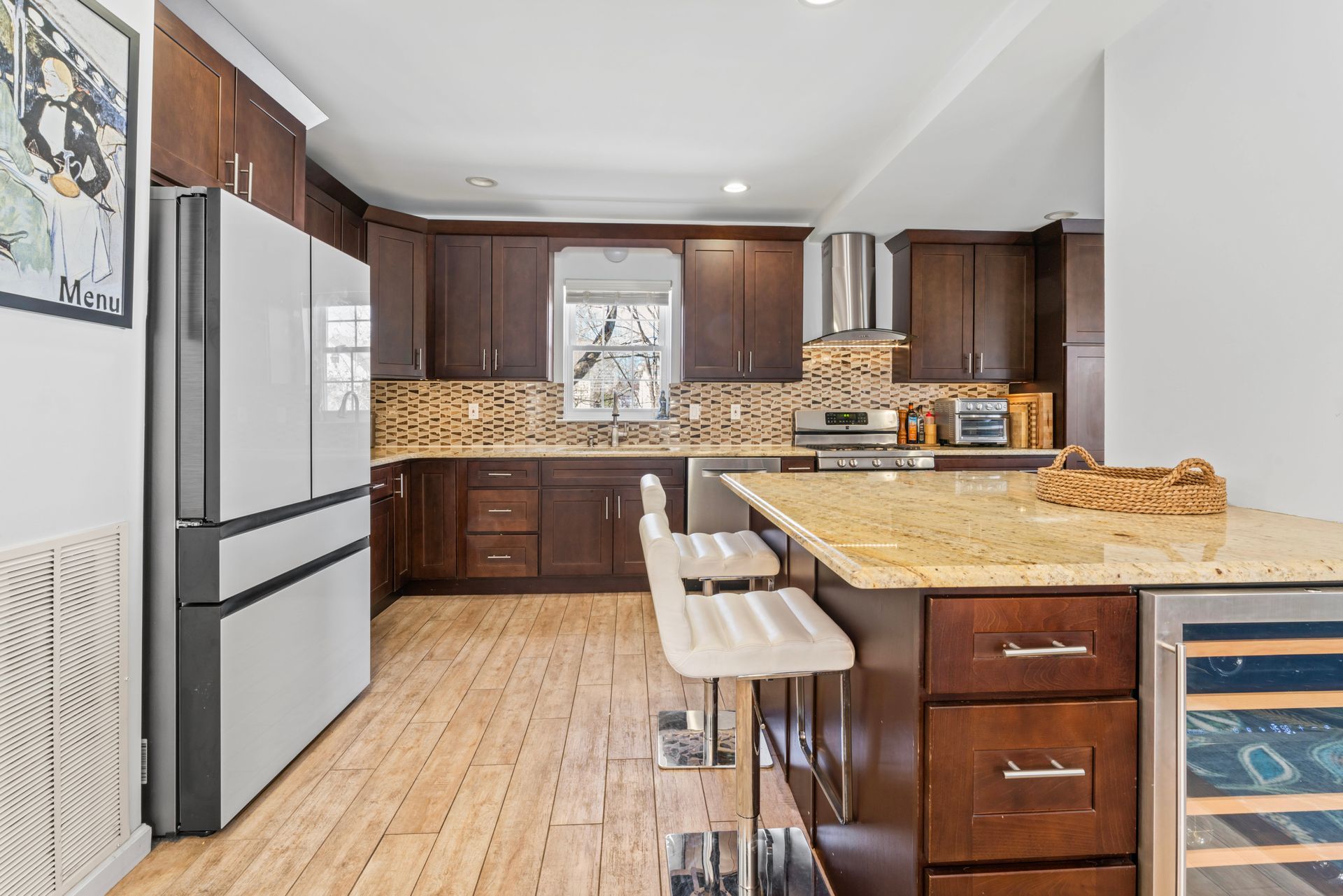 Kitchen with dark wood cabinets, island with stools, and stainless steel appliances.