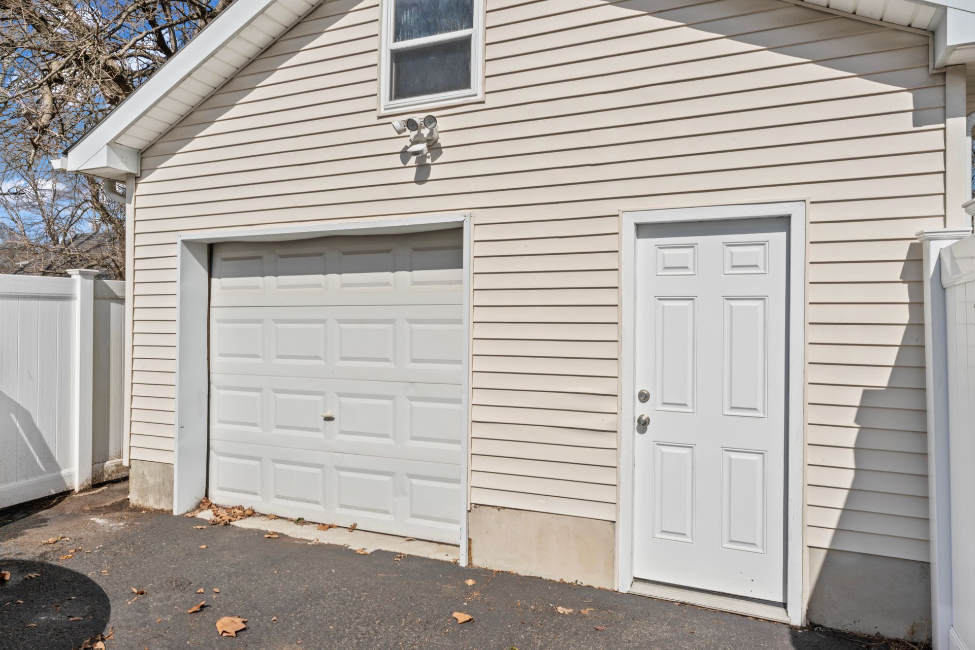 White garage with a door, light siding, and a small window.