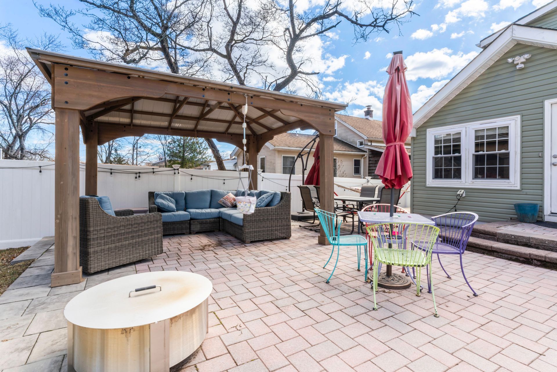 Patio with a gazebo, seating area, fire pit, and colorful table and chairs.