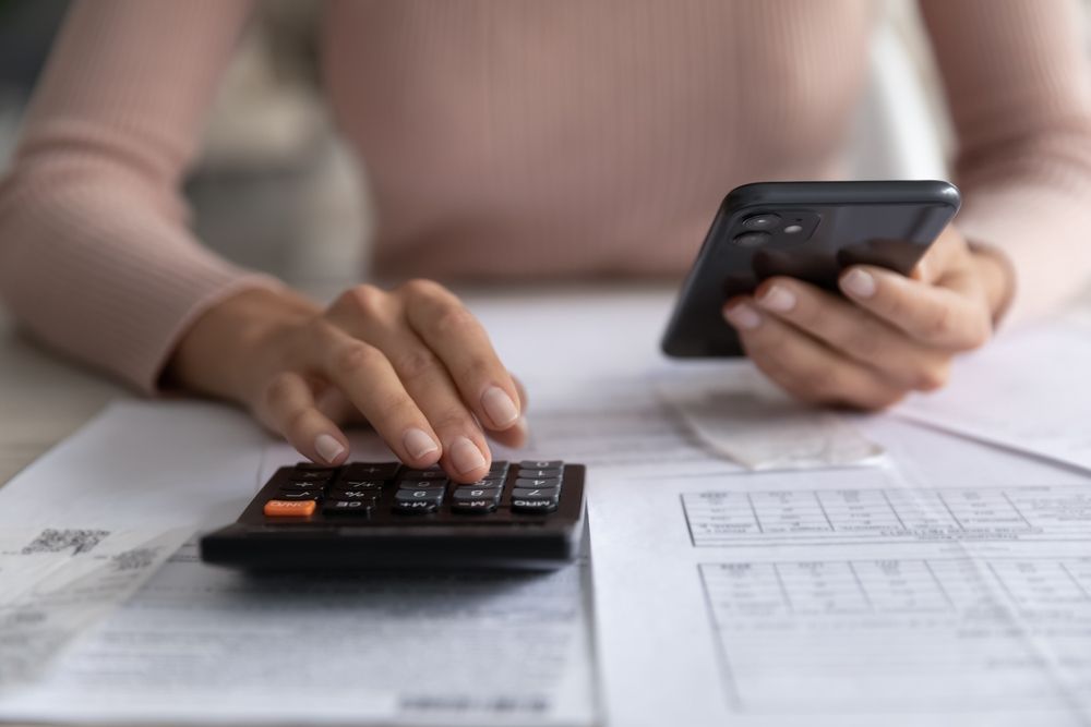 Person using a calculator and smartphone while reviewing paperwork. — Sunshine Office Solutions in Caloundra, QLD