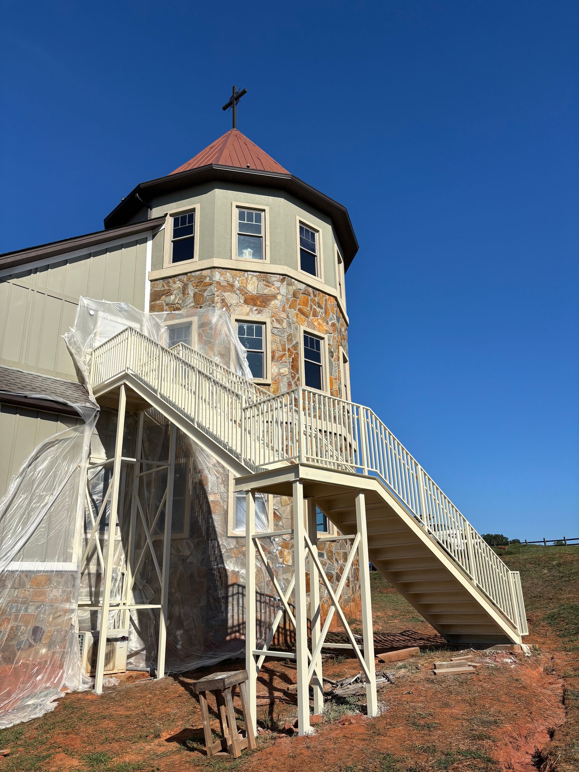 Historic lighthouse with white stairs and red roof under a clear blue sky