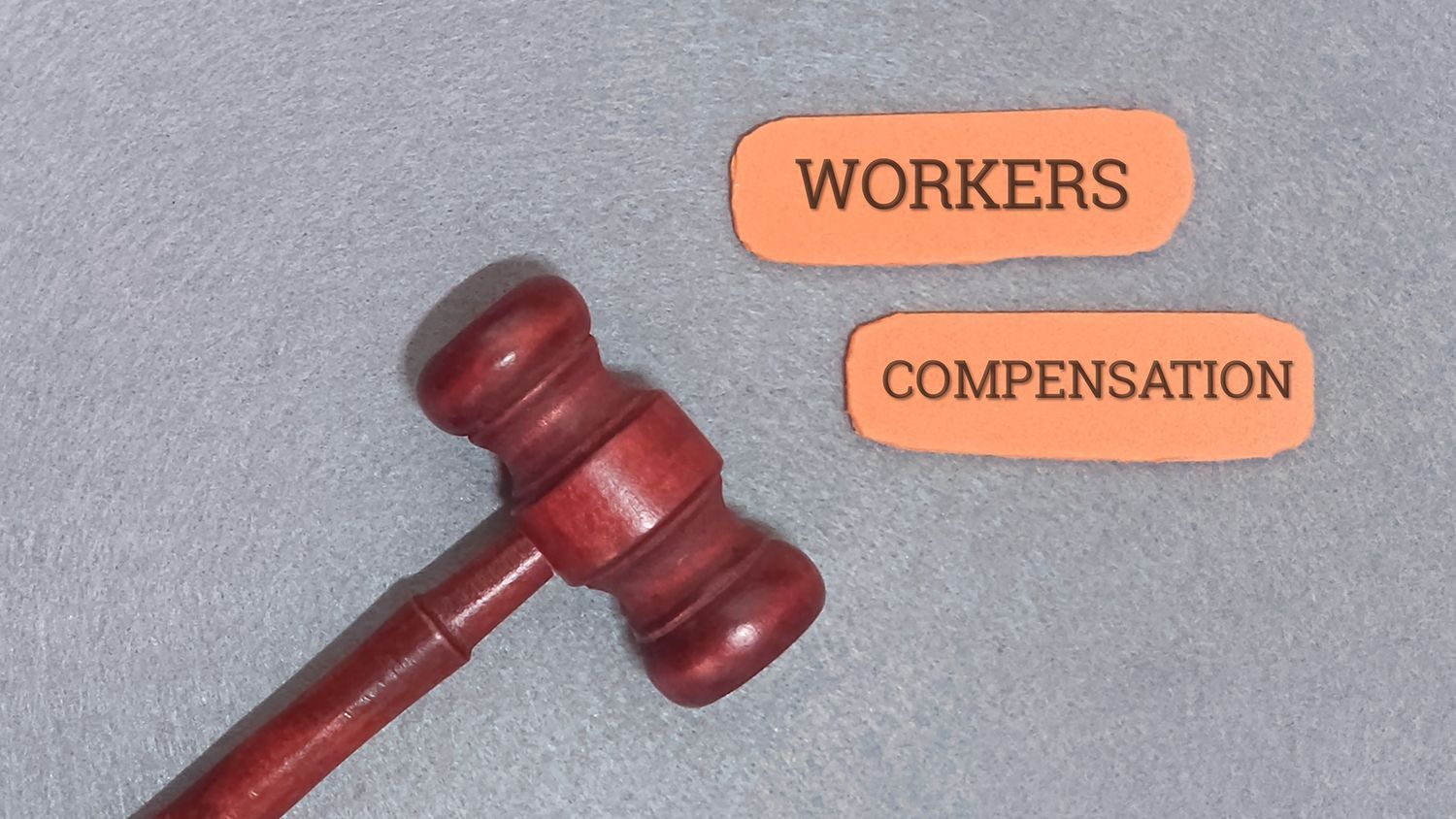 Wooden gavel with orange cutouts: “Workers Compensation,