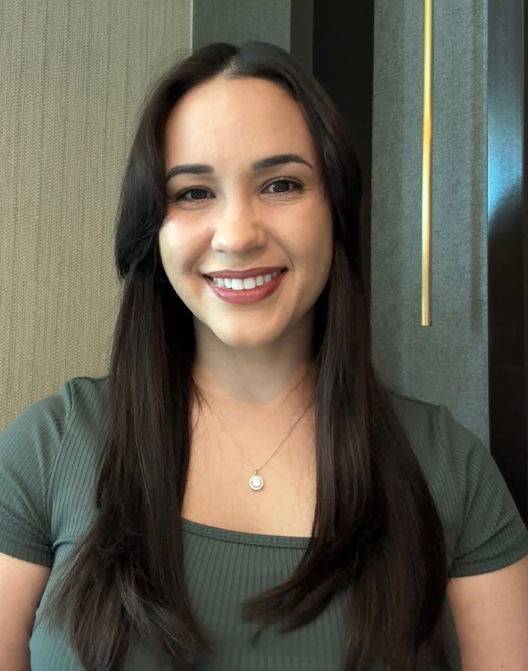 Shelly Rodriguez wearing a green shirt and a necklace smiles for the camera
