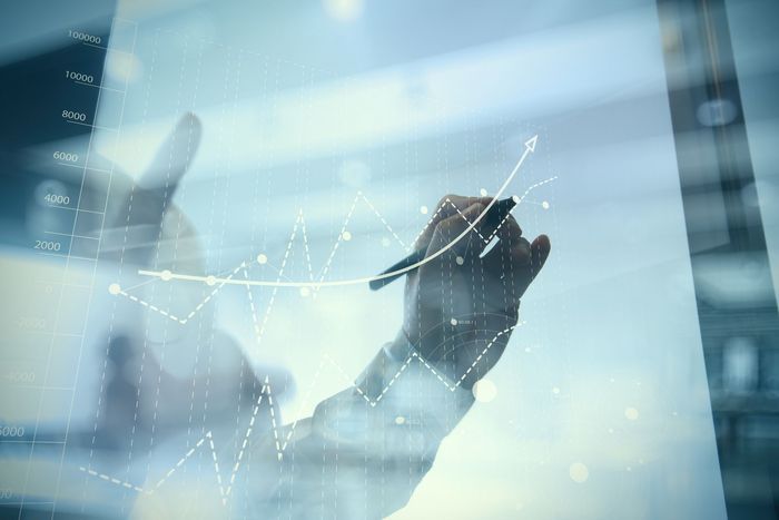 A person is drawing a graph on a glass wall with a pen.