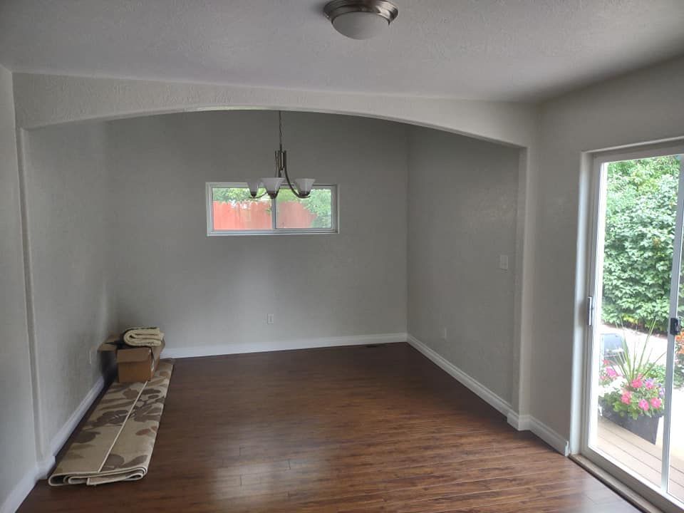 Empty dining room with wood floors, arched doorway, chandelier, and sliding glass door.