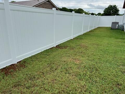 A white fence surrounds a lush green lawn in a backyard. Clarksville, TN