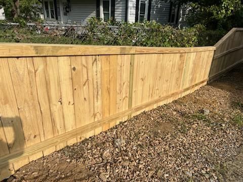A wooden fence is sitting on top of a gravel driveway next to a house. Clarksville,TN