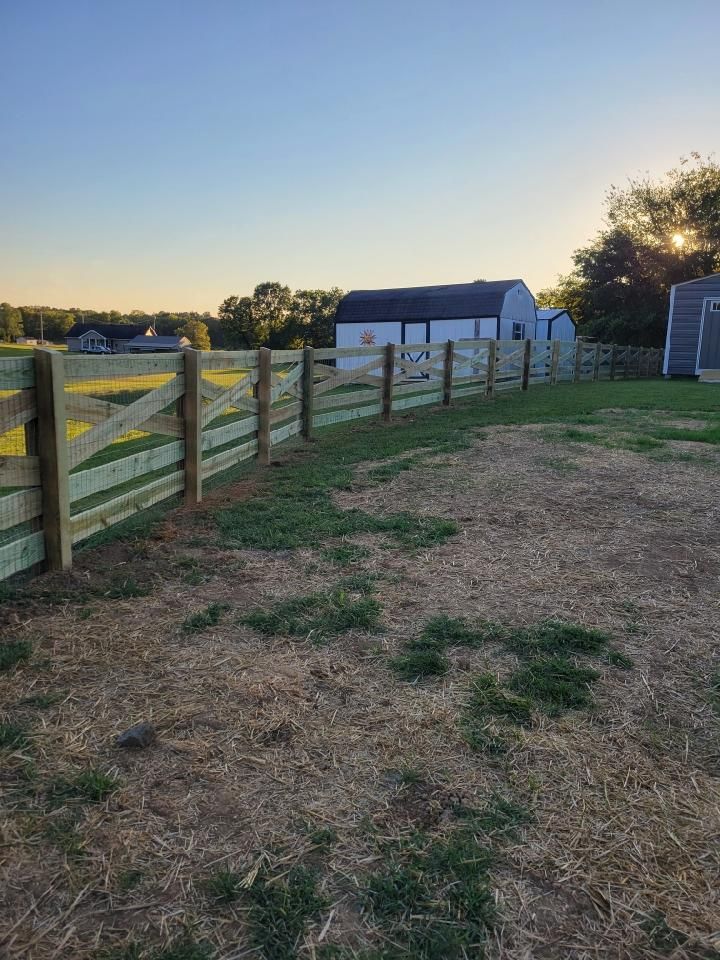 A wooden fence surrounds a grassy field with a barn in the background. Clarksville,TN