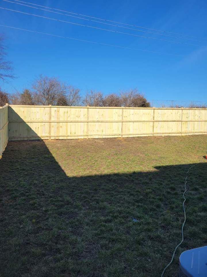 A backyard with a wooden fence and a blue sky in the background. Clarksville,TN