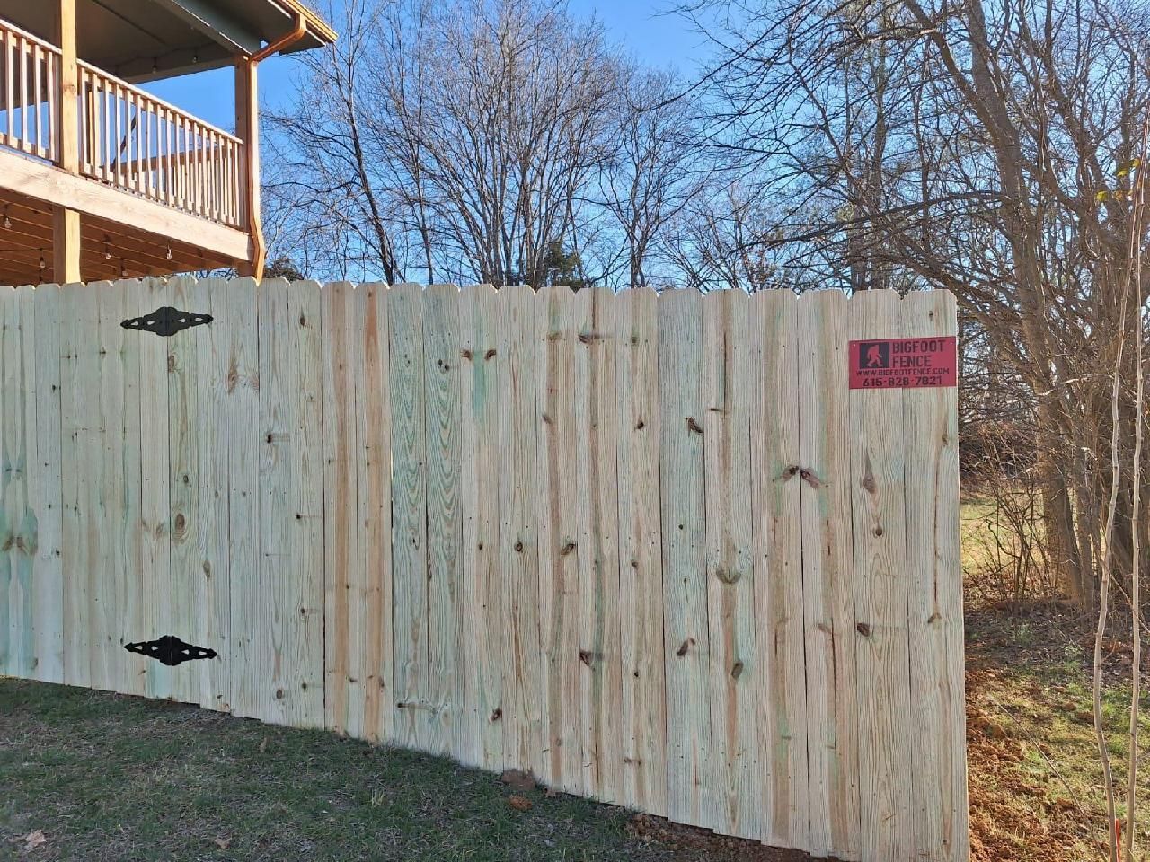 A wooden fence in front of a house with a balcony. Middle, TN