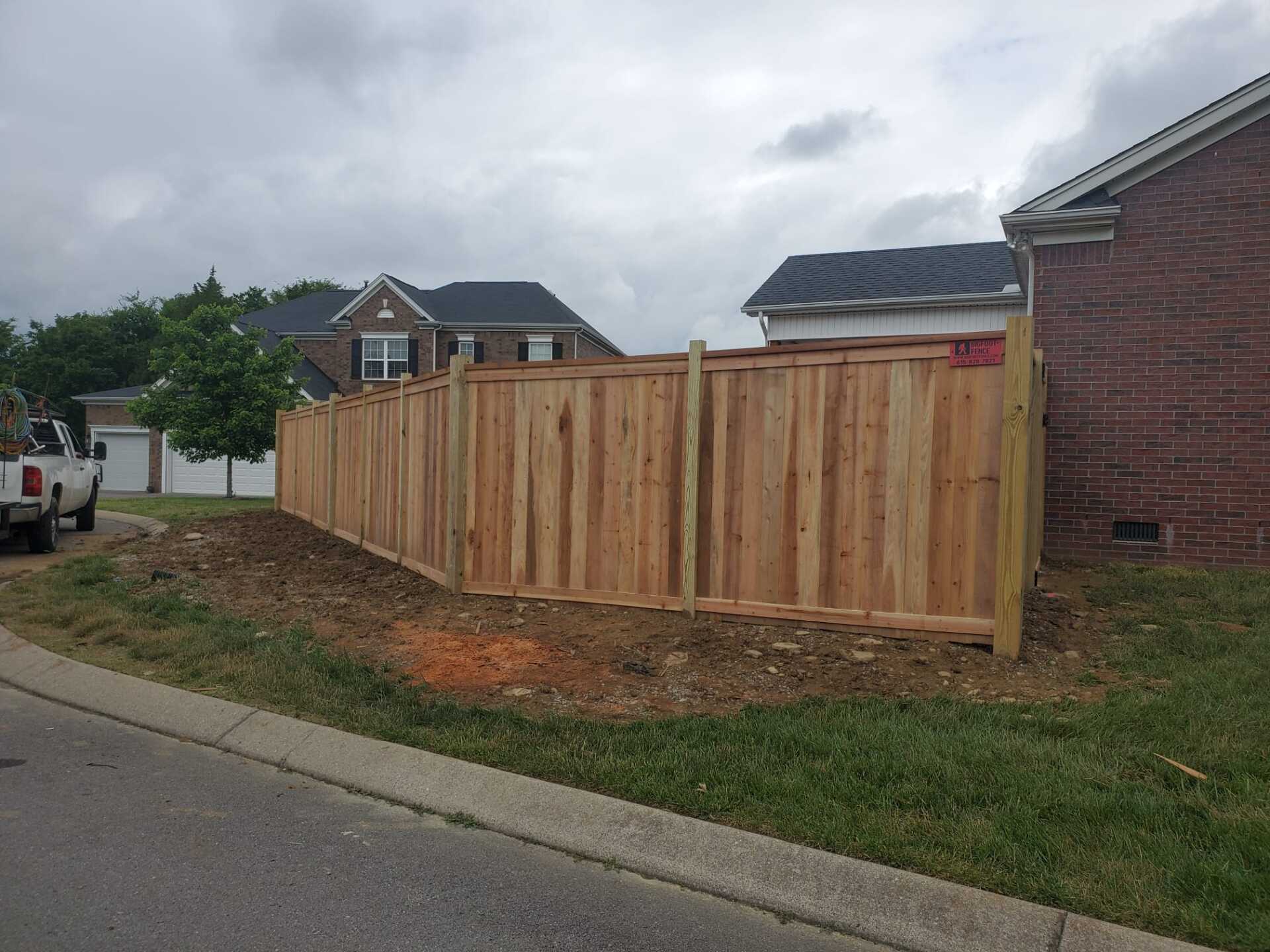 A wooden fence is being built in front of a brick house. Middle, TN