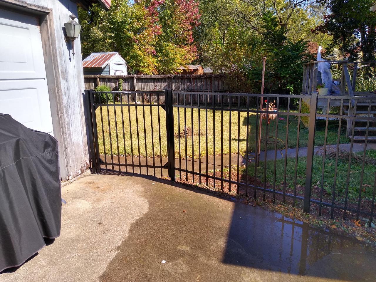 A black gate is sitting in the middle of a driveway next to a garage. Middle, TN