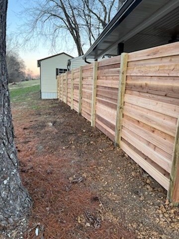 A wooden fence is sitting next to a tree in front of a house. Clarksville, TN