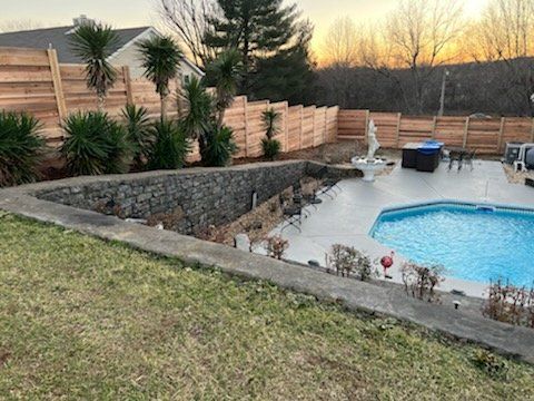 A large swimming pool is surrounded by a wooden fence and a stone wall. Clarksville, TN