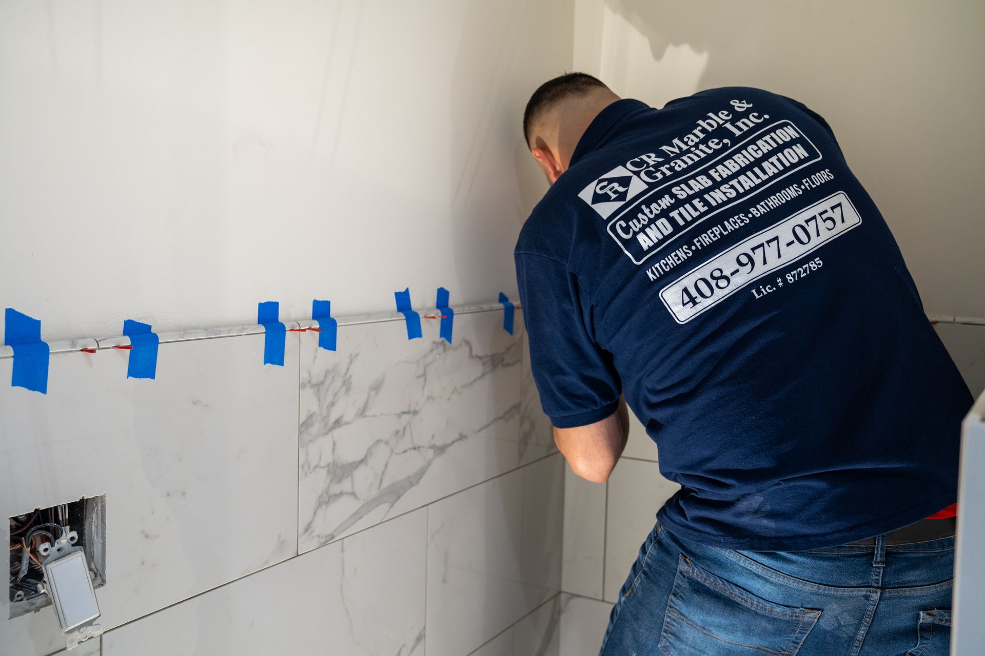 A man in a blue shirt is working on a wall.