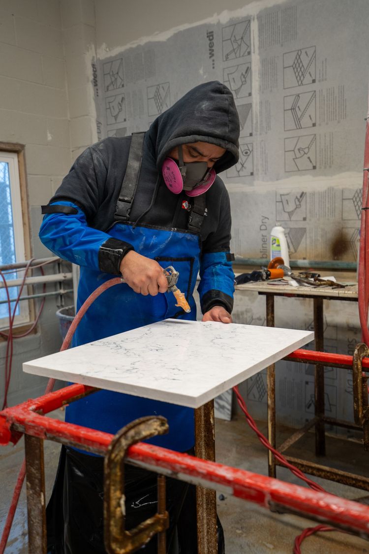 A man wearing a gas mask is cutting a piece of wood.