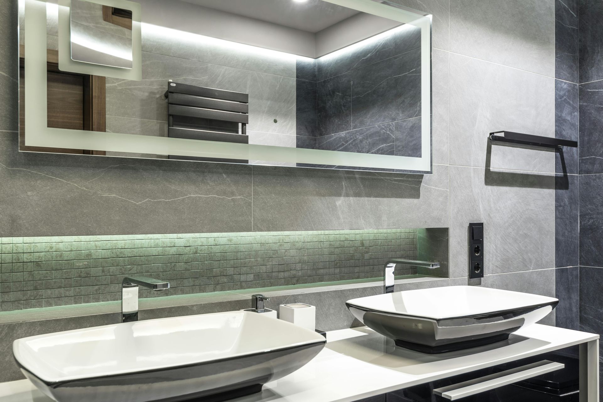 A bathroom with two sinks , a mirror and a towel rack.