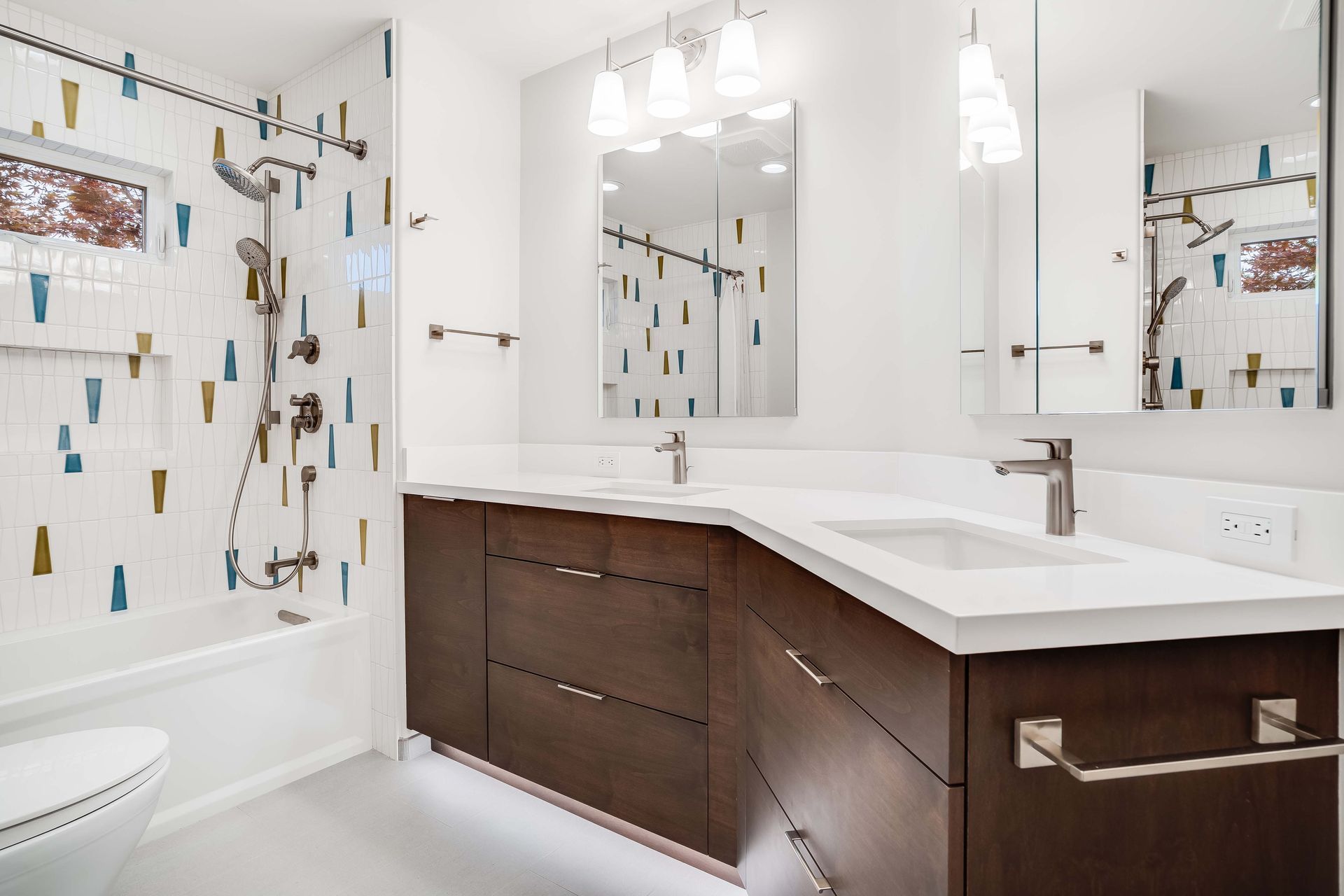 Modern bathroom with white countertops, dark wood vanity, patterned tile, and chrome fixtures.