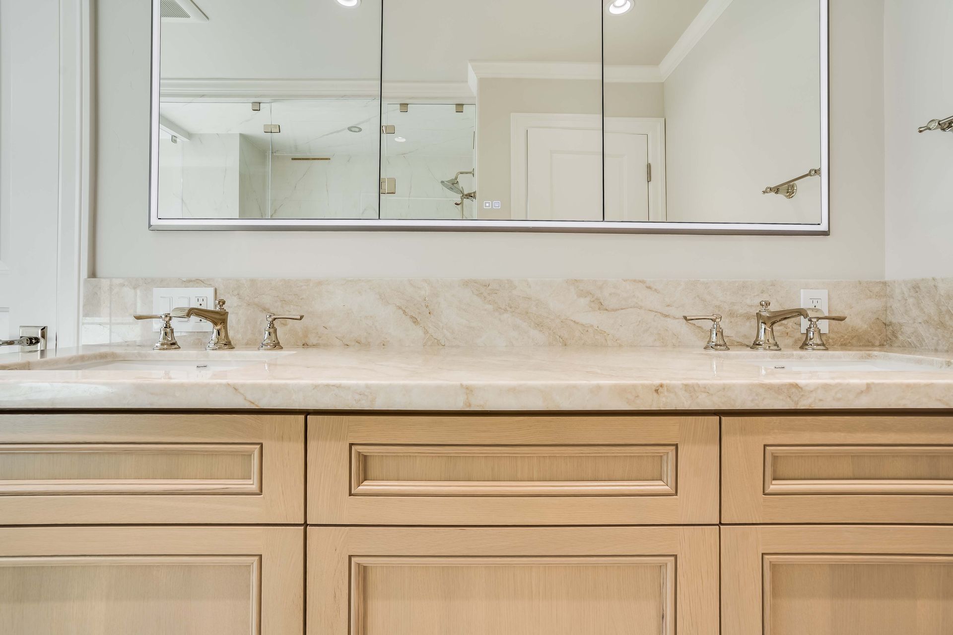 Bathroom with a light beige vanity, marble countertop, and triple mirrored medicine cabinet.