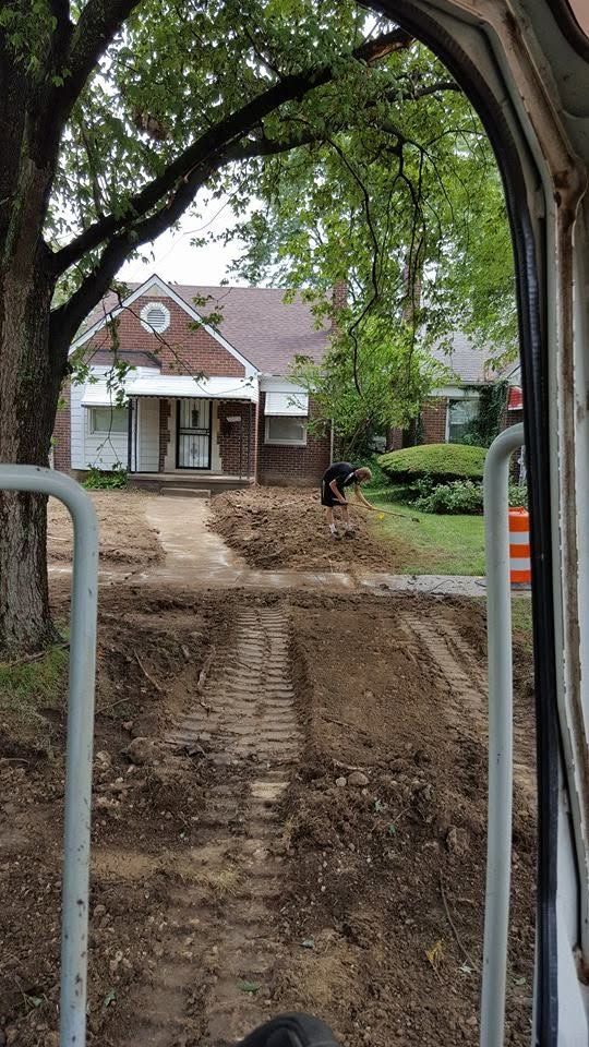 View from a doorway of a muddy yard with a small house and trees after excavation work