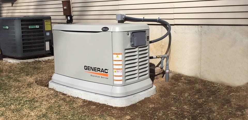 Outdoor Generac home backup generator beside a house, on a gravel pad.