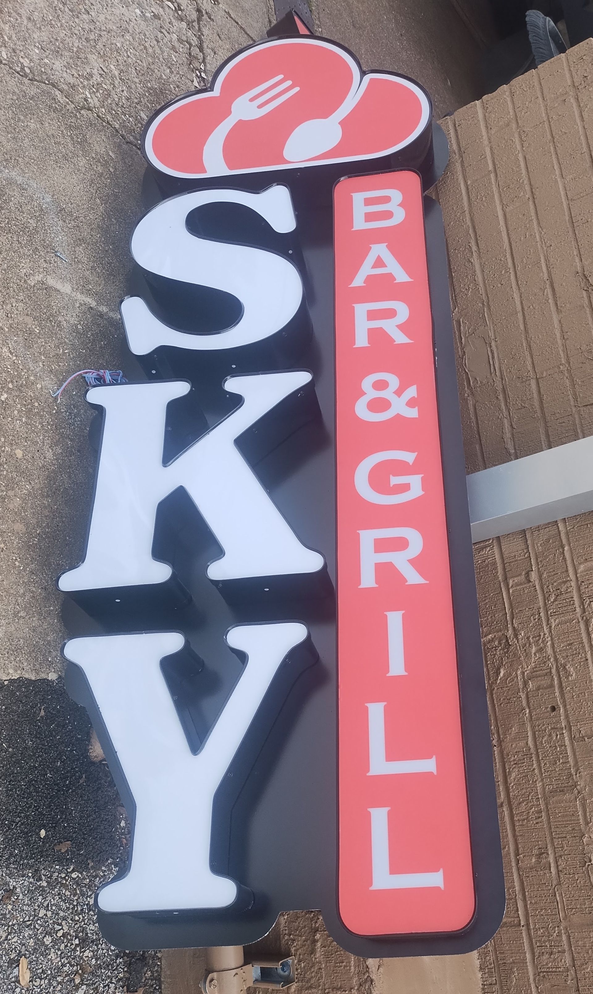 SKY BAR & GRILL vertical sign in black, red, and white with a steaming plate icon above the letters.