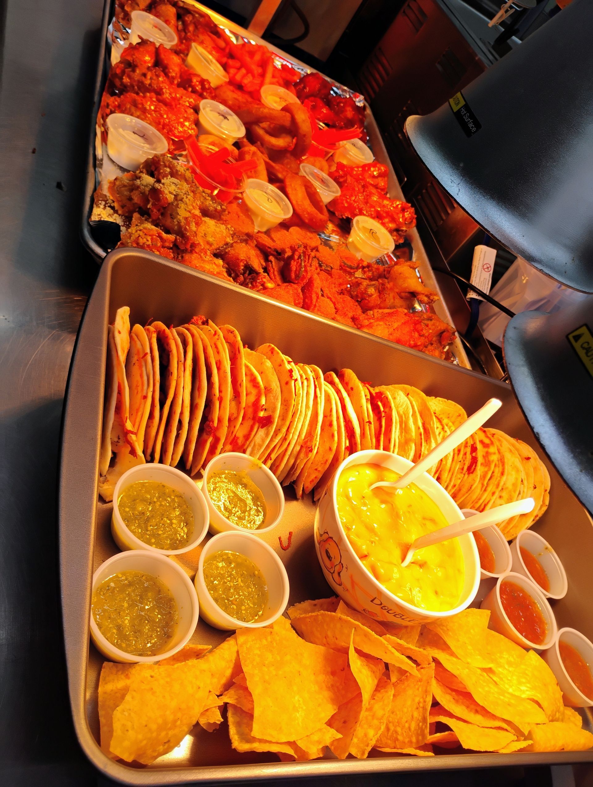 Buffet table with tacos, tortilla chips, salsas, and a red stew in trays